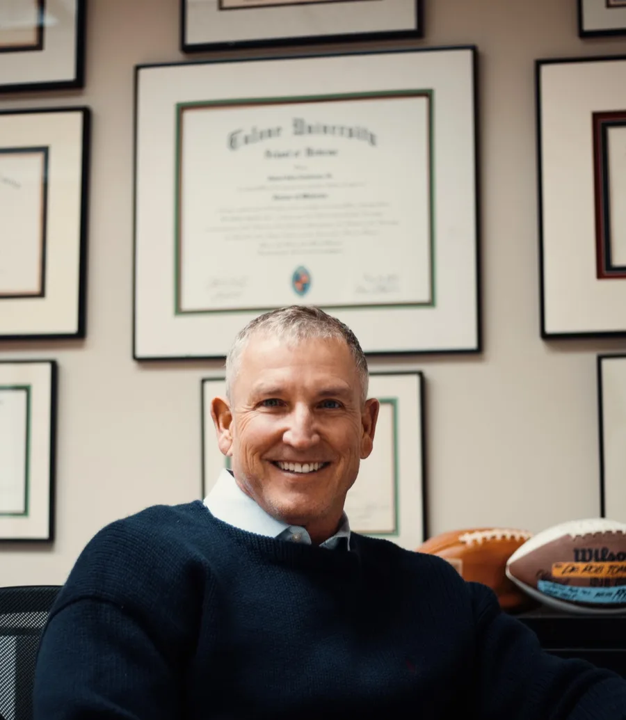 Dr. Robert Tomlinson, M.D., seated in his Fayetteville office in front of his framed Tulane University Doctor of Medicine diploma